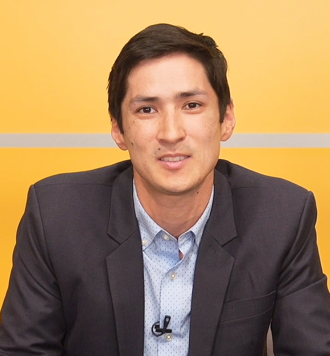Headshot of Greg Wallingford, a man with short dark hair wearing a dark suit jacket and light blue button down shirt looking at the camera.