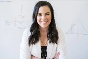 Headshot of Katelyn Jetelina, Ph.D., MPH, a white woman with long dark hair in a white blazer and black shirt smiling at the camera with her arms crossed.