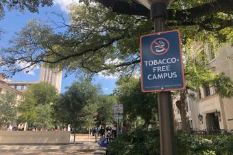 UT Austin tobacco-free campus sign with students and UT tower in the background