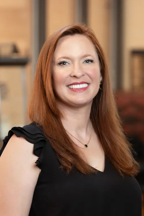 Headshot of Dr. Ashley Garling, a white woman with mid-length auburn hair wearing a black top and smiling at the camera