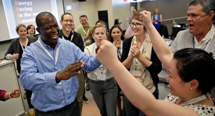 A group of HCLI attendees participating in the annual Rock, Paper, Scissors tournament and cheering each other on.